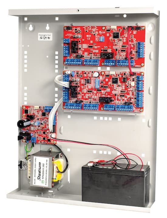 Open electrical enclosure containing red circuit boards, a transformer, and a black backup battery.
